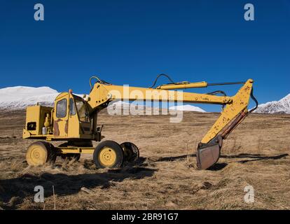 Un vecchio giallo digger era parcheggiata nel mezzo di un prato in Islanda Foto Stock