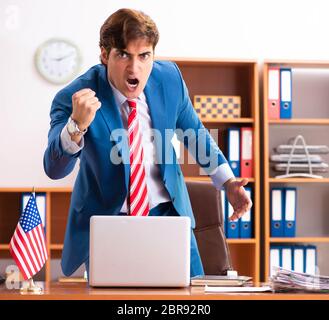 Il giovane uomo politico bello seduto in ufficio Foto Stock