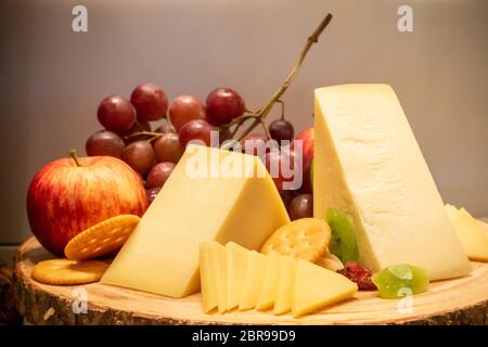 Formaggio gruviera con varietà di frutta e cracker sul piatto di legno in linea a buffet Foto Stock