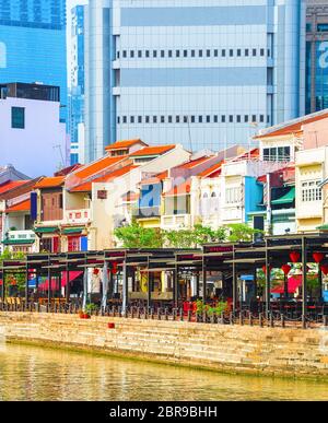 Paesaggio con colorati bar, ristoranti e negozi da Singapore River lungo Boat Quay, grattacieli di architettura moderna in background Foto Stock