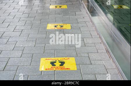 Mantenere gli adesivi Social Distancing incollati sul pavimento di fronte al ristorante in Qatar Foto Stock