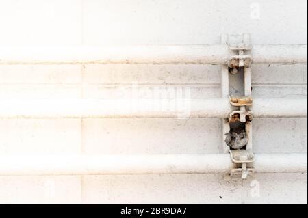 Tre tubi di acqua industriale con ruggine sulla parete bianca nell'area della fabbrica. Foto Stock