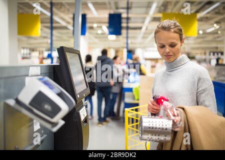 Piuttosto, giovane donna scegliendo i prodotti giusti per il suo appartamento in un moderno arredamento home store (toni di colore immagine; shallow DOF) Foto Stock