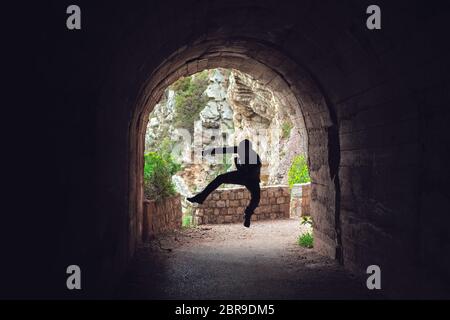 Silhouette di un uomo a praticare il karate mosse e tecniche in un buio del tunnel Foto Stock