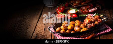 Datteri rustici avvolti in pancetta e patate giovani arrostite. Foto Stock