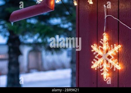 Stella elettrica appesa fuori casa in legno durante il periodo di Natale in inverno Foto Stock