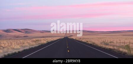 Luce rosa inonda il cielo di Alba nel lungo lonely autostrada Foto Stock