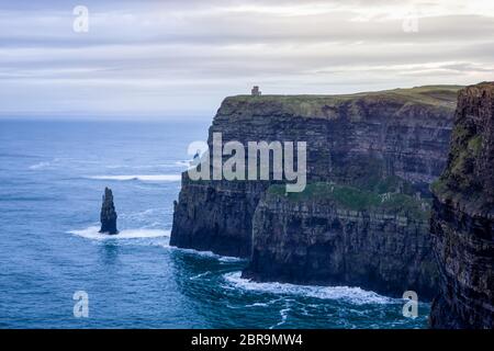 Scogliere iconiche di Moher in Wild Atlantic Way con rovine di torre sul bordo di alta scogliera, bellissimo cielo drammatico sullo sfondo, Irlanda Foto Stock