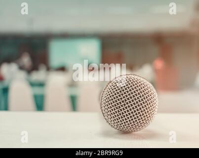 Primo piano microfono wireless vecchio sul tavolo in conferenza e sfondo sfocato interno sala riunioni seminario. Colore tonalità vintage Foto Stock