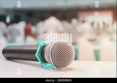 Primo piano microfono wireless vecchio sul tavolo in conferenza e sfondo sfocato interno sala riunioni seminario Foto Stock