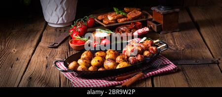 Datteri rustici avvolti in pancetta e patate giovani arrostite. Foto Stock