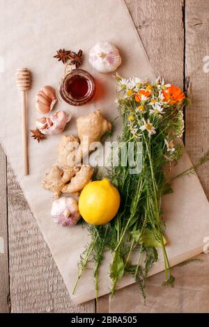 Vasetto di miele biologico, limone, radice d'aglio, anice, camomilla di fiori freschi e calendula. Concetto di medicina alternativa, omeopatia, influenza stagionale calda t Foto Stock