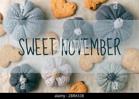 Sweet NIVEMBER testo, la natura morta autunnale di zucca lavorata a mano, biscotti a forma di cuore su carta da forno. Concept caldo casa accogliente stagione autunno co Foto Stock