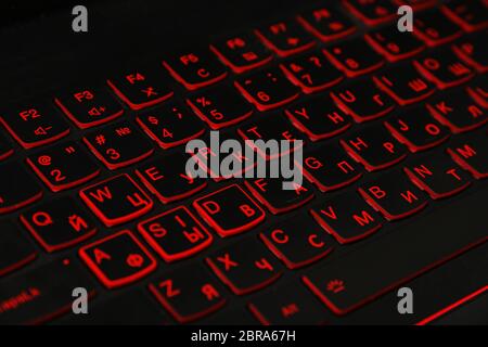 Close up rosso LED retroilluminato laptop computer tastiera con doppio alfabeto, Inglese e cirillico, ad alto angolo di visione Foto Stock