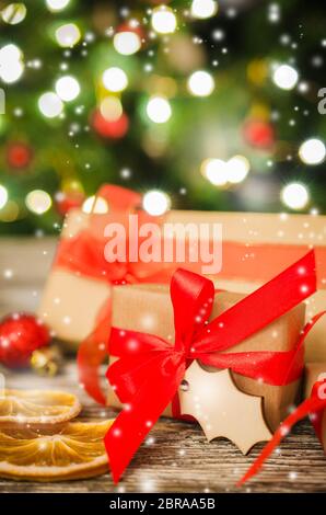 Regalo di natale scatole legate con nastri rosso contro lo sfondo di albero di Natale e bokeh di scintillanti luci di partito. Vista con lo spazio di copia Foto Stock