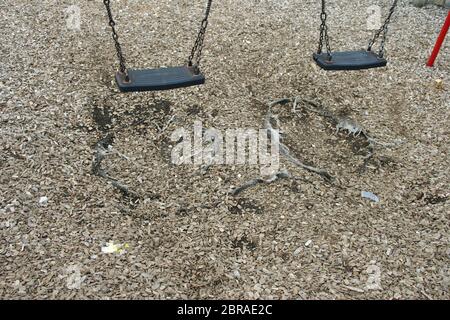 Due park swing dove la corteccia scheggiata è stato usurato e il materassino sotto è stata danneggiata. Foto Stock