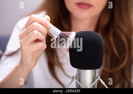 Donna che utilizza la spazzola sul microfono per rendere i suoni ASMR Foto Stock