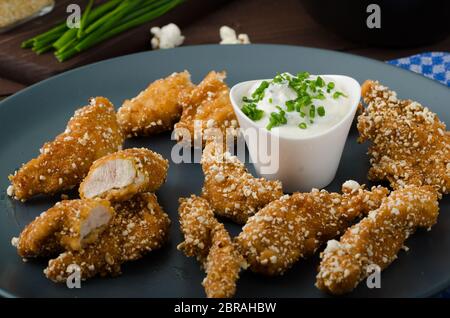 Le strisce di pollo nel pangrattato popcorn, con deliziosi aglio dip panini e toast Foto Stock