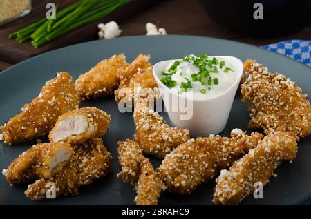 Le strisce di pollo nel pangrattato popcorn, con deliziosi aglio dip panini e toast Foto Stock