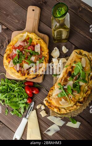 Calzone pizza, riempito di erbe, formaggio e pomodori Foto Stock