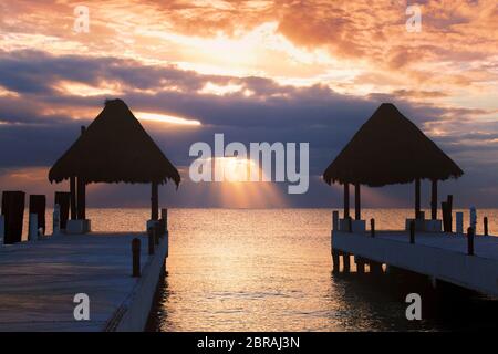 I raggi del sole si infrangono attraverso le nuvole all'alba a Puerto Morelos, Quintana Roo sulla Riviera Maya del Messico. Foto Stock