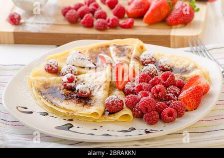 Frittelle fatte in casa con riduzione di balsamico e frutta fresca, fragole e lamponi Foto Stock
