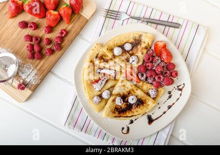 Frittelle fatte in casa con riduzione di balsamico e frutta fresca, fragole e lamponi Foto Stock