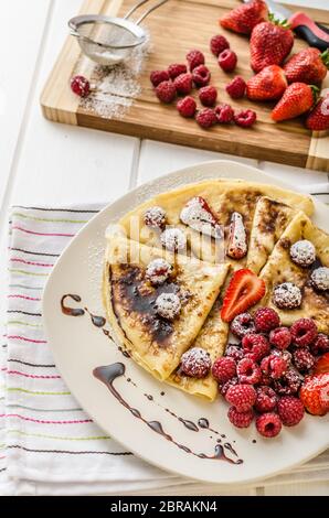 Frittelle fatte in casa con riduzione di balsamico e frutta fresca, fragole e lamponi Foto Stock
