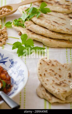 Pane libanese, pane pita, ceci freschi e piacevoli sullo sfondo, pane semplice a buon mercato con erbe e aglio Foto Stock