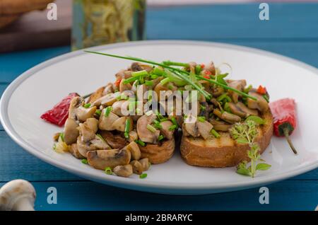 La bruschetta 2 tipi - classic con pomodoro, basilico e mozzarella, secondo tipo con funghi, il peperoncino e le erbe aromatiche Foto Stock