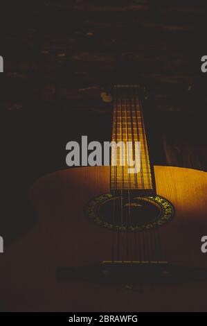 Chitarra acustica vicino al buio, illuminate da un fascio di luce Foto Stock