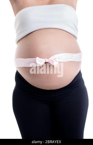 Primo piano di archetto rosa sopra il ventre della donna incinta su sfondo bianco Foto Stock