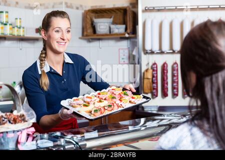 Donna di vendita nel macellaio che offre il finger food e servizio di festa Foto Stock