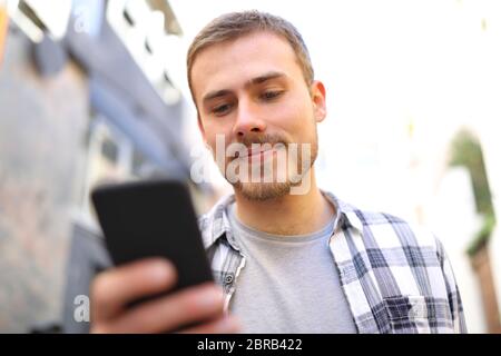 Uomo serio è a piedi utilizzando un telefono intelligente nelle strade di una città vecchia Foto Stock