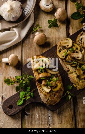 Rustico pane tostato con aglio, funghi e erbe aromatiche, dallo stile rustico foto Foto Stock