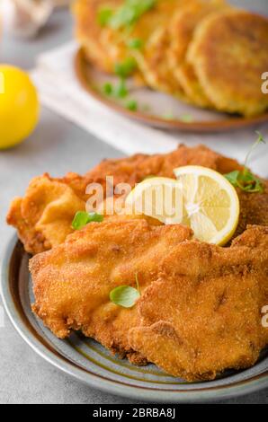 Deliziosa schnitzel originale con frittelle di patate, succo di frutta fresco, frittelle con aglio ed erbe Foto Stock