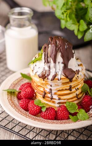 Frittelle americane con icecream e cioccolato, erbe e bacche intorno Foto Stock