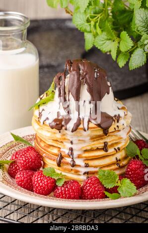 Frittelle americane con icecream e cioccolato, erbe e bacche intorno Foto Stock