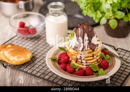 Frittelle americane con icecream e cioccolato, erbe e bacche intorno Foto Stock