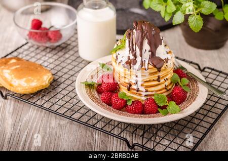 Frittelle americane con icecream e cioccolato, erbe e bacche intorno Foto Stock