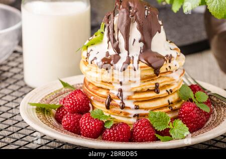 Frittelle americane con icecream e cioccolato, erbe e bacche intorno Foto Stock