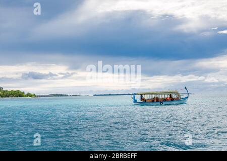 Spiaggia tropicale bianca nelle Maldive con palme e Dhoni tradizionale in laguna blu Foto Stock