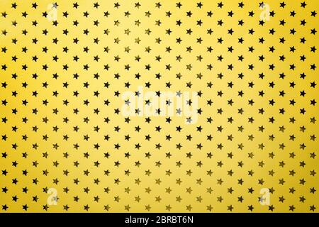 Sfondo dorato da carta di metallo con un motivo di closeup stelle scintillanti. Struttura di carta metallizzata gialla per la vacanza con vi Foto Stock