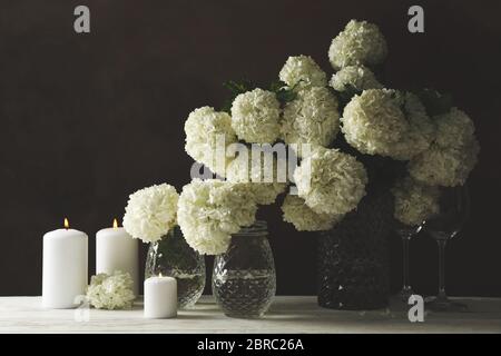 Composizione con fiori di idrangea e candele su sfondo marrone. Serata romantica Foto Stock