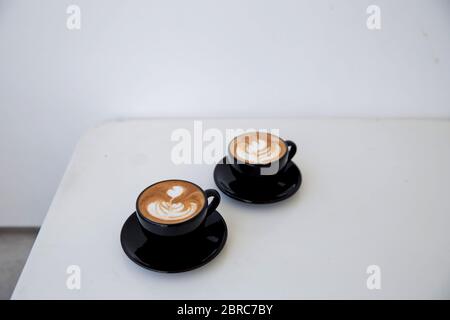 Due tazze di cappuccino caldo su sfondo bianco di legno. Posiziona per il testo. Foto Stock