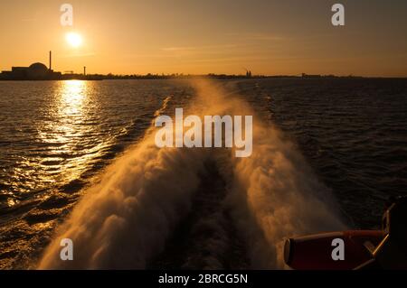 Una centrale nucleare vista da una nave al tramonto Foto Stock