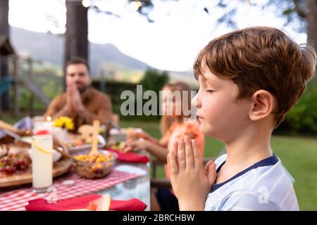 Famiglia caucasica che dice grazia insieme prima di mangiare Foto Stock