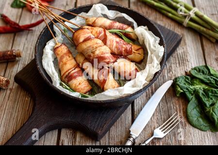 Arrotolare con pancetta e trito di pollo su uno stufato con asparagi freschi e spezie Foto Stock