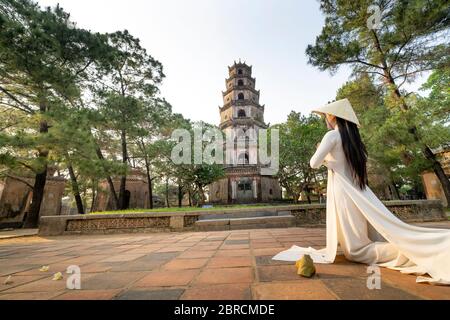 Hue City, Thua Thien Hue Province, Vietnam - 7 maggio 2020: Una scena di una ragazza in un costume tradizionale di ao dai che prega all'interno di un tempio Foto Stock