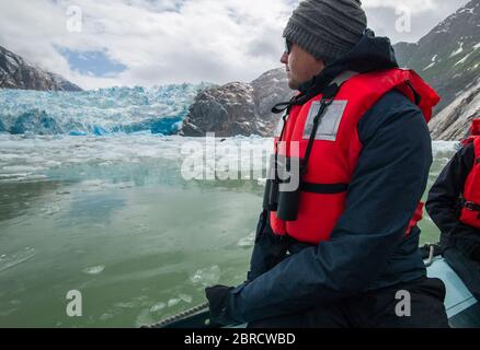 Il turista su una barca da sci da crociera avventura della piccola nave guarda gli iceberg calved dal ghiacciaio di South Sawyer, Tracy Arm Fjord, Alaska sudorientale, Stati Uniti. Foto Stock